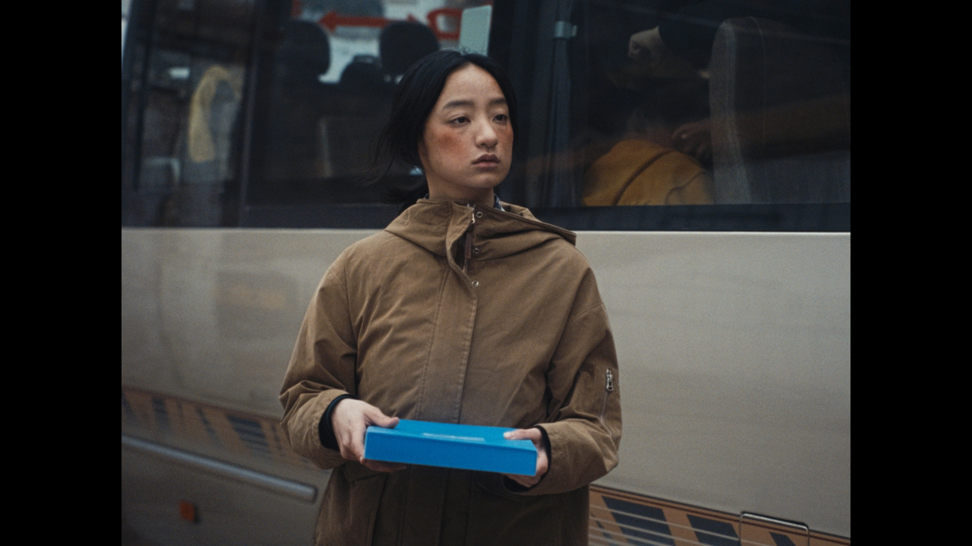 车旁拿着蓝色盒子的女孩